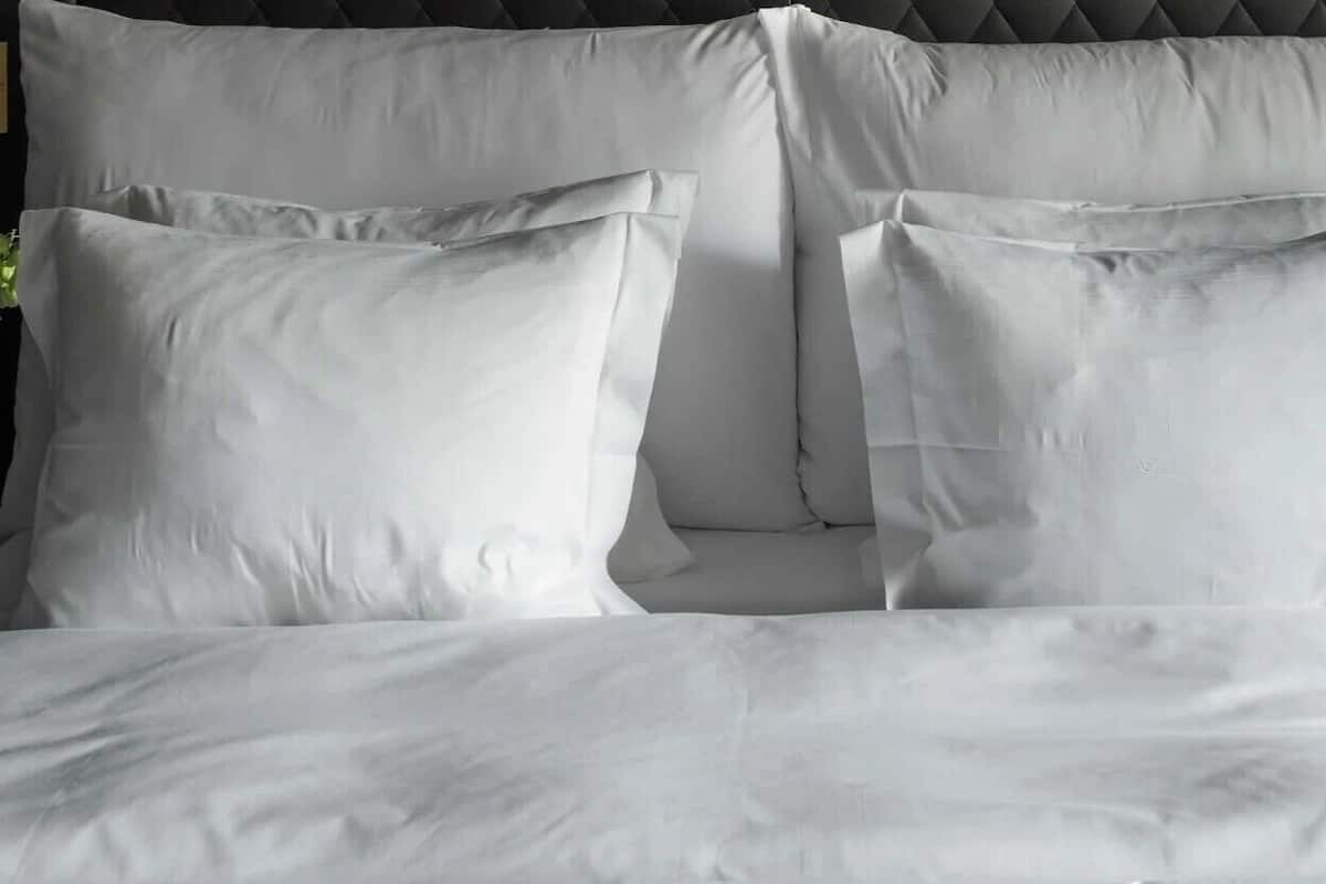 Ein Bett mit weißen Bettwäsche und zwei Kissen.