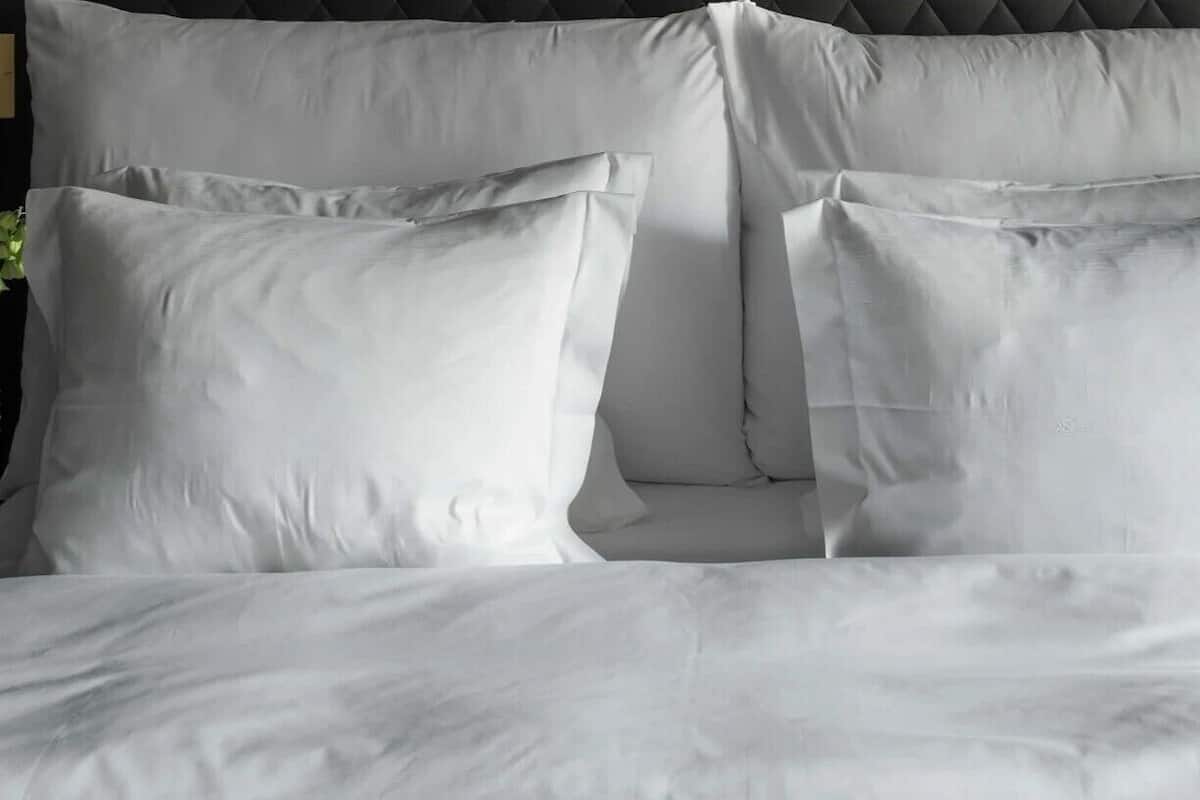 Ein Bett mit weißer Bettwäsche und Kissen.