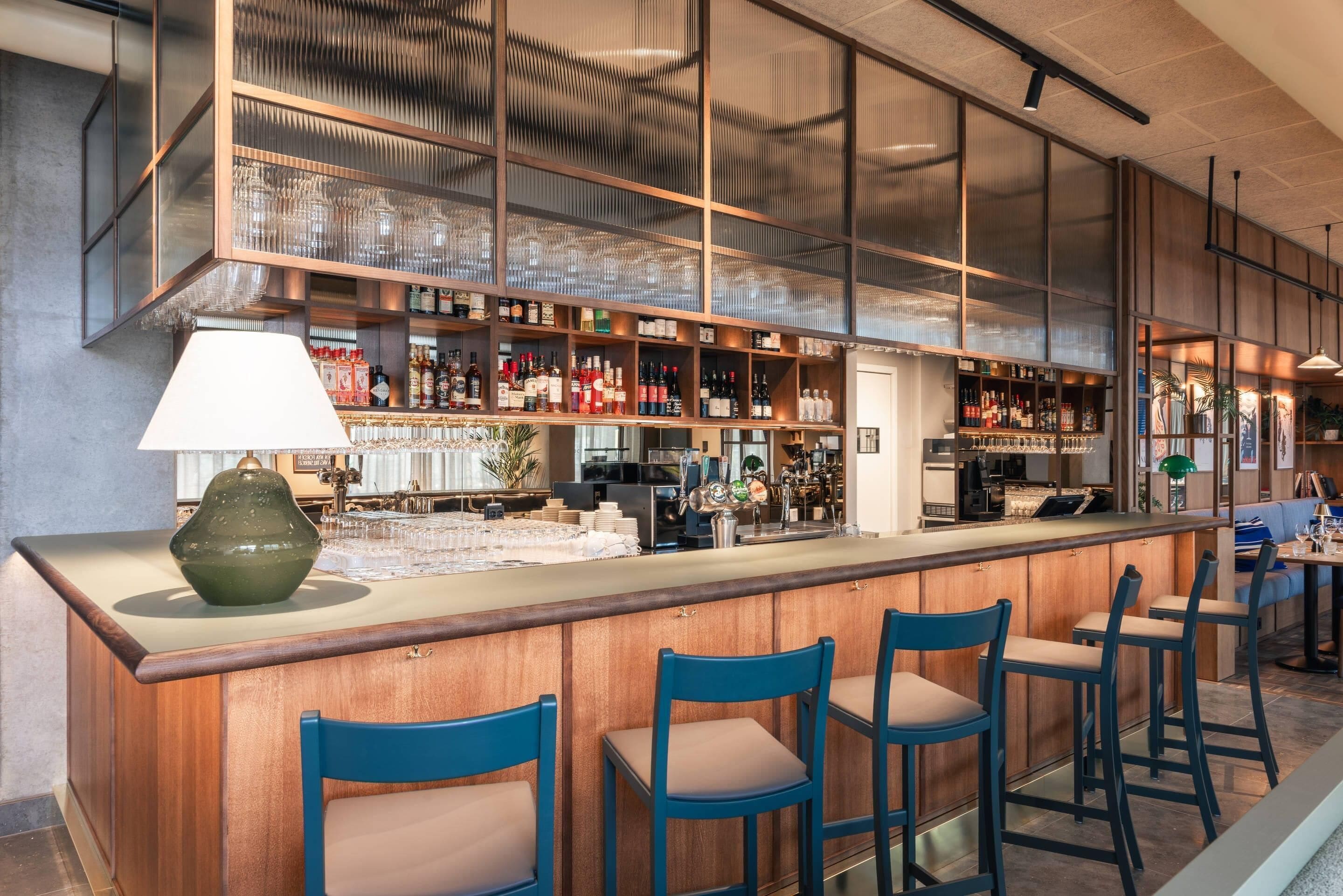 A bar area with a counter, stools, and shelves of bottles.