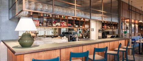 A bar area with a counter, stools, and shelves of bottles.