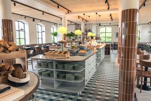 Un restaurante espacioso con techos altos, ventanas amplias y piso de tablones.