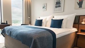 A hotel room with a bed, a nightstand, a lamp, and a view of the outdoors. - Quality Hotel The Book (Gothenburg)