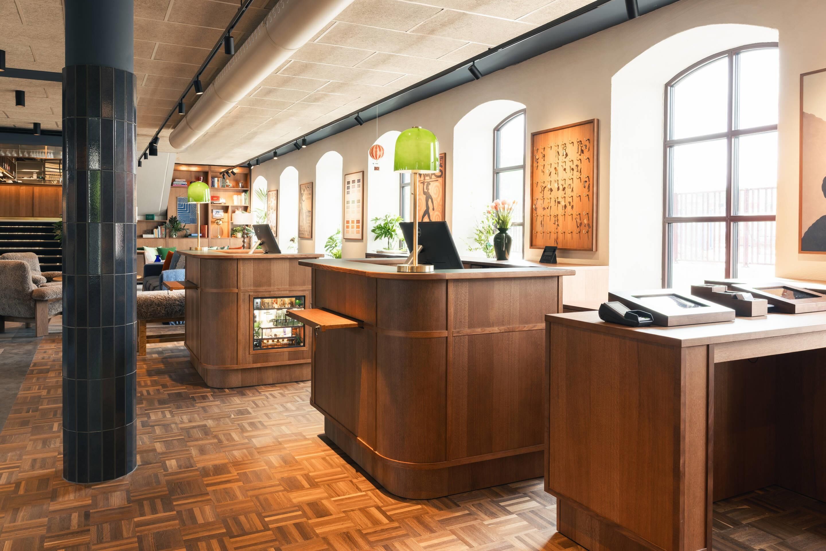 A reception area with wooden reception desks, a herringbone floor pattern, and large windows with arched tops.