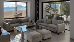 A modern living room with a large window, a sofa set, a coffee table, and a tall shelving unit. - The Breeze of Carthage Earthly Paradise (Carthage)
