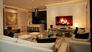 A modern living room with a fireplace, a television, and a dining area. - The Breeze of Carthage Earthly Paradise (Carthage)