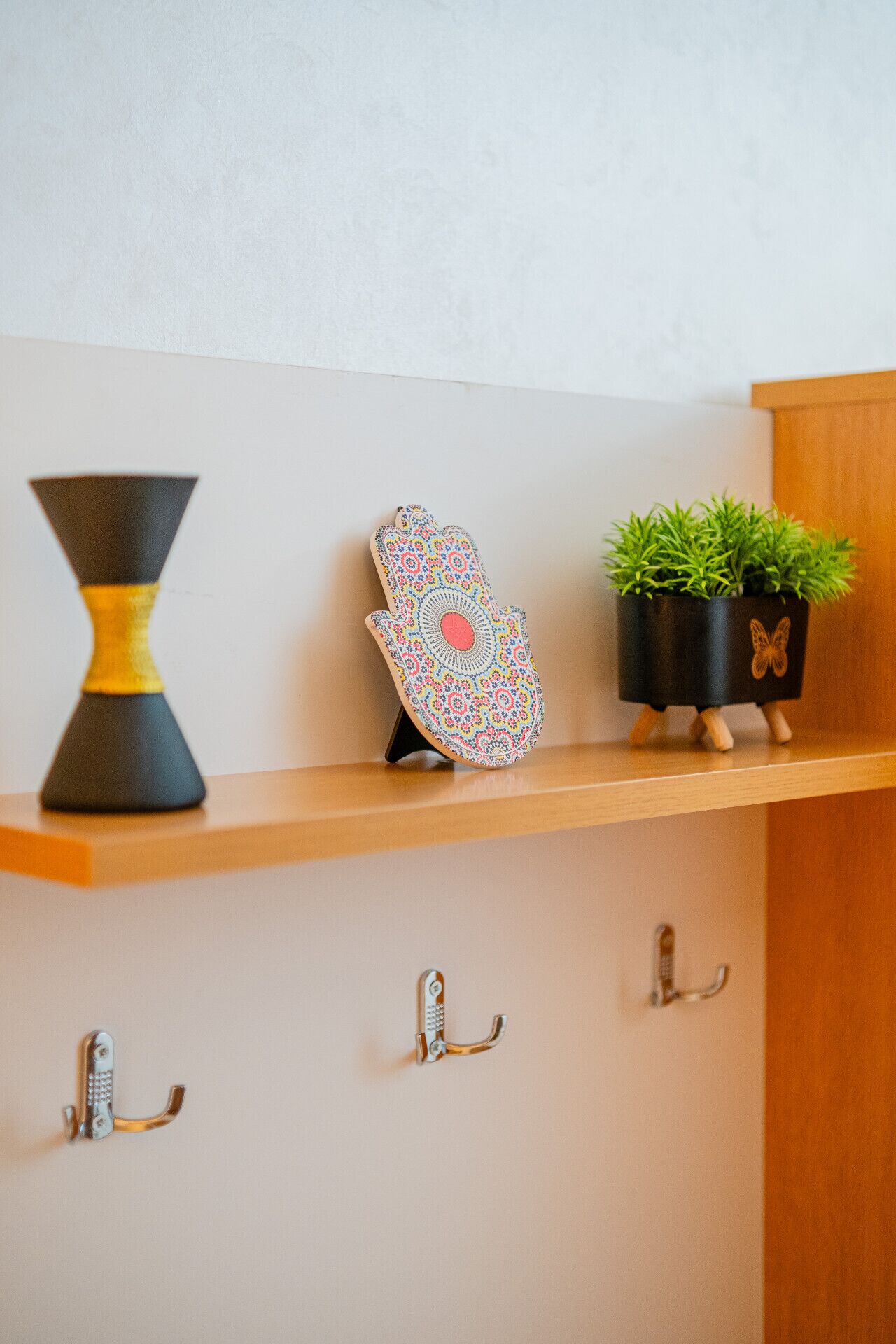 Une étagère ornée d’un vase décoratif, d’un plateau à motifs et d’une plante en pot.