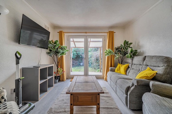 Bright lounge with sofa seating, TV, and patio doors to the garden