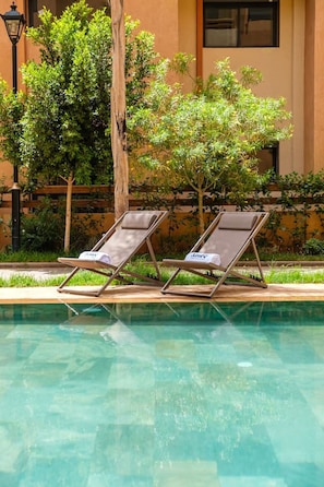 A poolside area with two lounge chairs and a lamp post. - Grand Duplex 4BR – Jacuzzi, Terrasses & Piscines (Marrakesh)