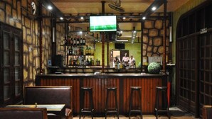 A bar with wooden walls, a counter with stools, and a television screen. - HOTEL CHEZ AGNES  (Dakar)