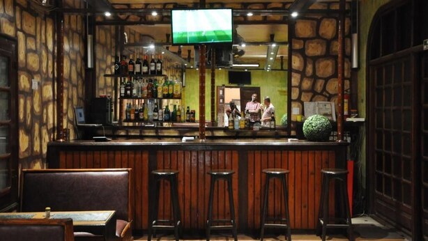 A bar area with a counter, stools, and a television screen. - HOTEL CHEZ AGNES  (Dakar)
