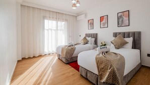 A hotel room with two beds, a large window with sheer curtains, a red rug, and framed artwork on the wall. - 2 min M-avenue / Guéliz Clim, Piscines & Parking (Marrakesh)