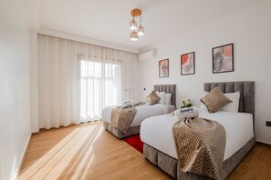 A hotel room with two beds, a large window with sheer curtains, a red rug, and framed artwork on the wall. - 2 min M-avenue / Guéliz Clim, Piscines & Parking (Marrakesh)