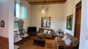 Una sala de estar acogedora con techo de madera, un televisor, dos sofás, una mesa de centro y un espejo.