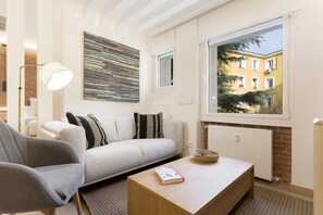 A modern living room with a sofa, a coffee table, a lamp, and a large window with a view of buildings. - Genteel Home Concha Espina II (Madrid)