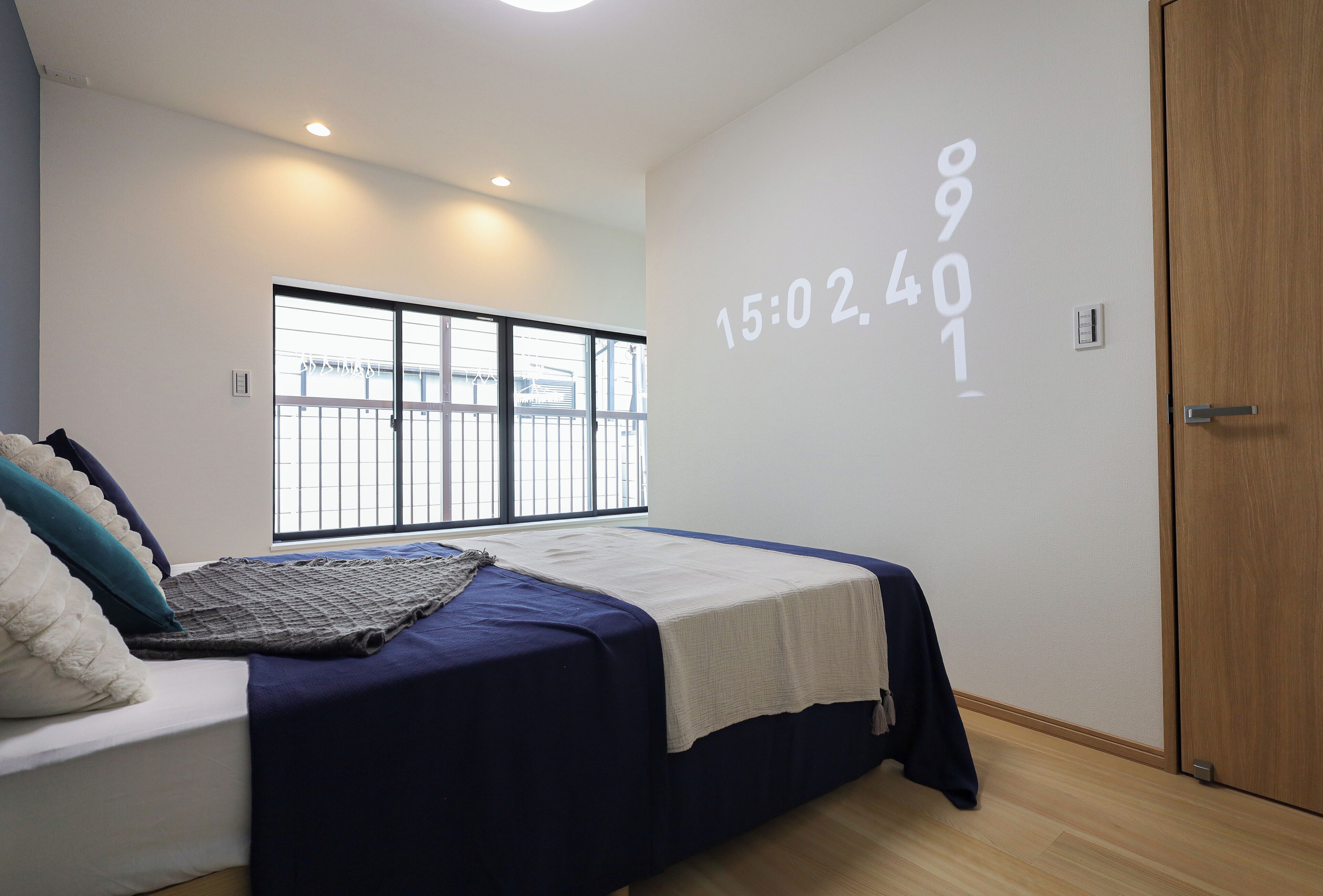 Un dormitorio moderno con una cama grande, una ventana con vistas y una pared con proyección de reloj digital.