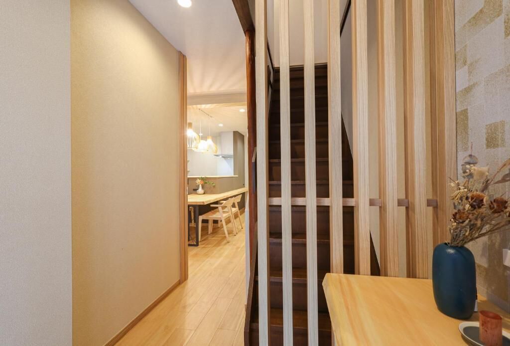 A hallway with a wooden staircase leading to a dining area.