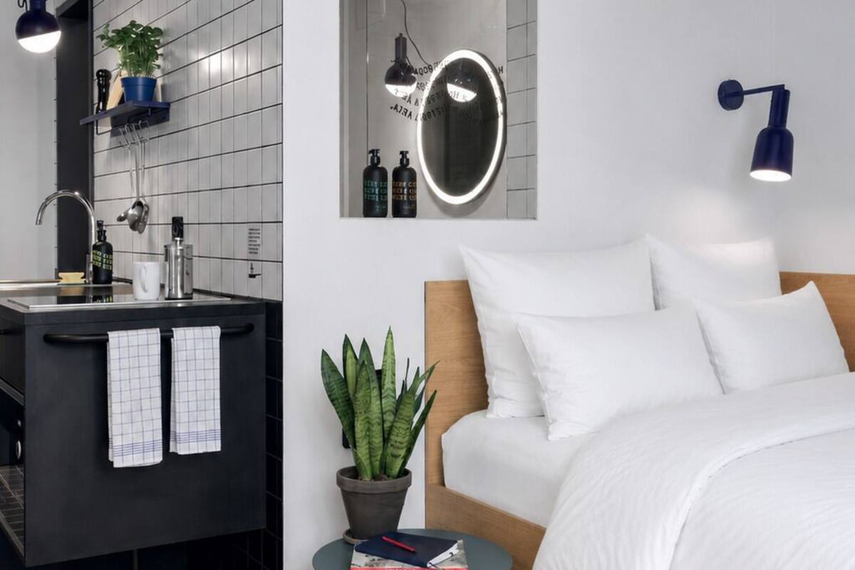 A modern bedroom with a bed, bedside table, and a small potted plant.