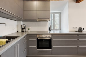 A modern kitchen with stainless steel appliances, a built-in oven, and grey cabinetry.