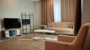 A modern living room with a sofa, a TV, a coffee table, and a bookshelf. - Suitev (Arnavutkoy)