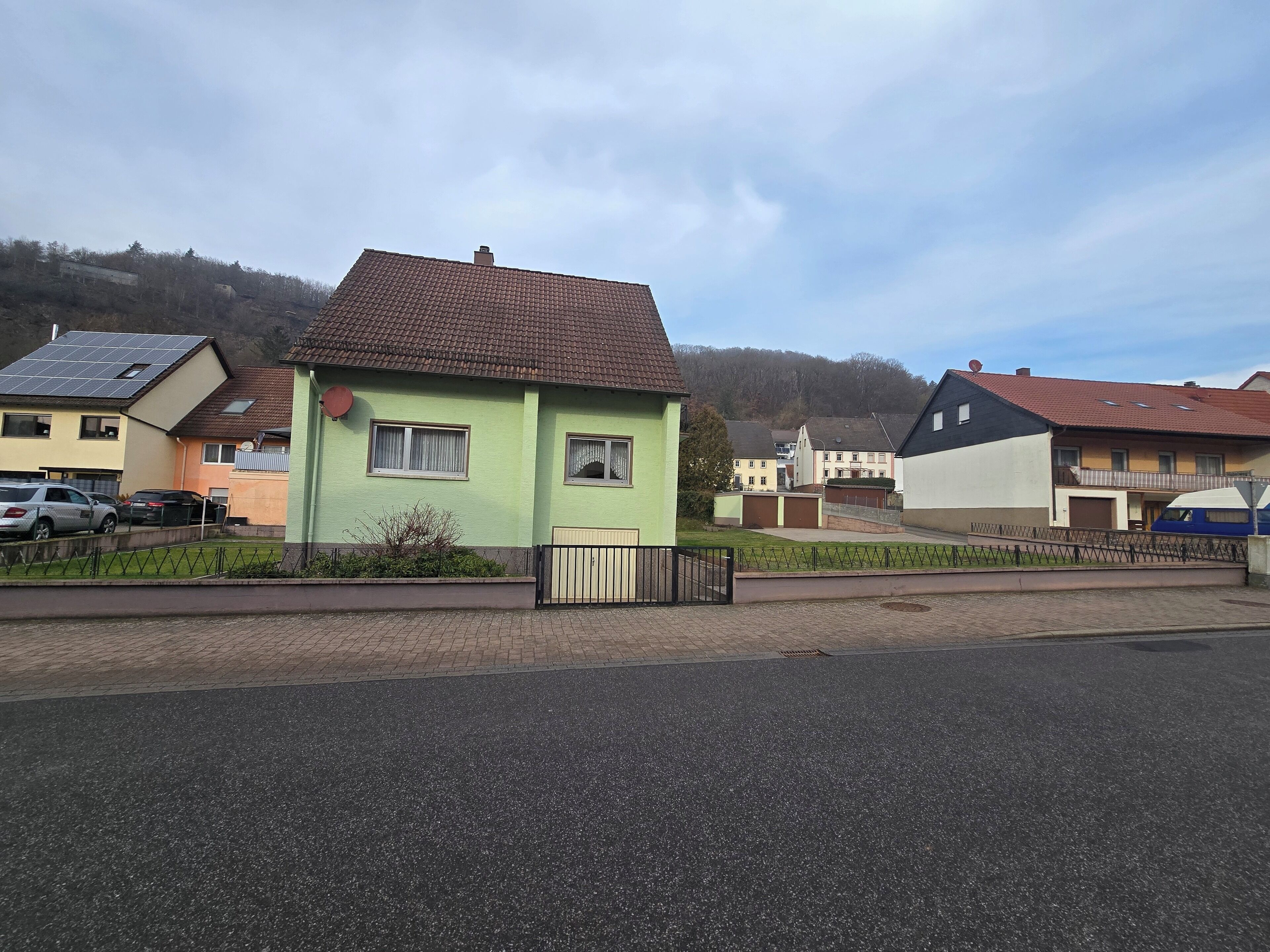 Ein Wohngebiet mit Häusern, einer gepflasterten Straße und einem Zaun.
