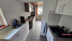 A modern kitchen with white cabinetry, a coffee maker, a toaster, and a sink. - Vacation home Lautertal-Lodge with private pool/whirlpool for up to 10 people (Kreimbach-Kaulbach)