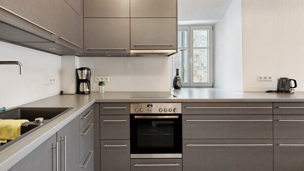 Eine moderne Küche mit Edelstahlgeräten, einem eingebauten Backofen und grauen Schränken.