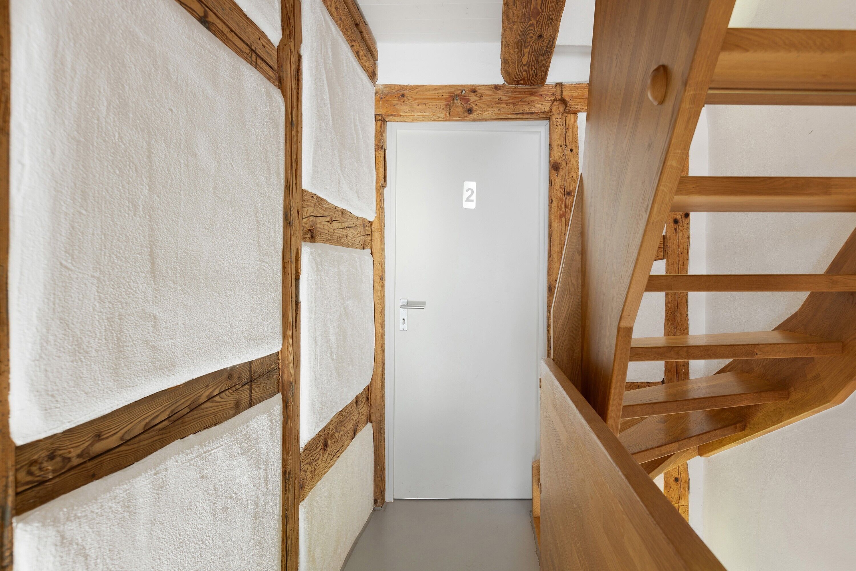 Una escalera de madera que conduce a una puerta blanca con el número 2.