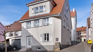 Ein zweistöckiges Gebäude mit rotem Ziegeldach, weißen Fensterläden und einer Steinsockel.