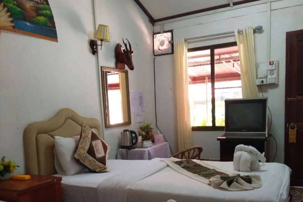 A hotel room with two beds, a television, a window with curtains, and a painting on the wall.