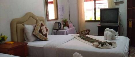 A hotel room with two beds, a television, a window with curtains, and a painting on the wall.