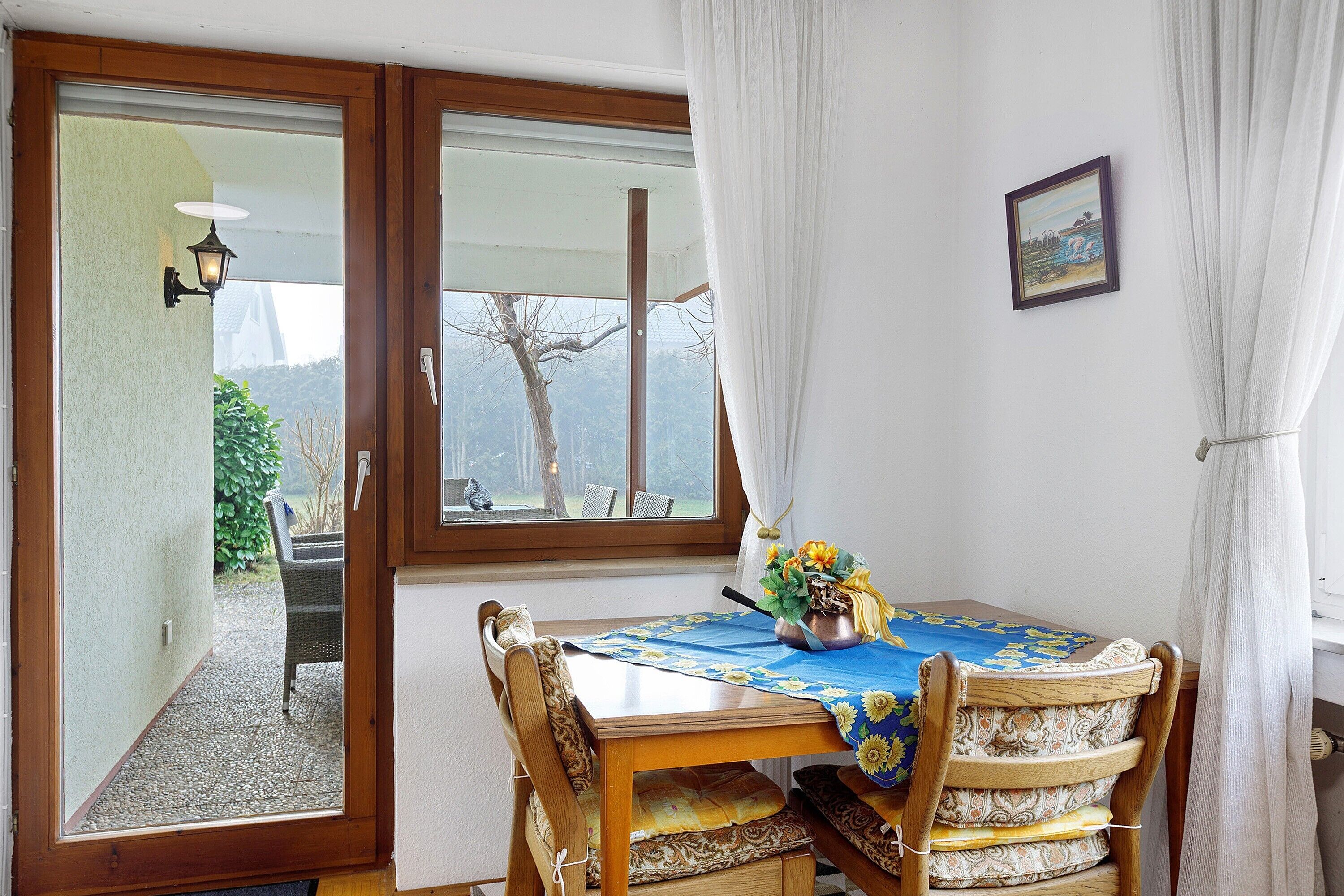 Ein Essbereich mit Tisch, Stühlen, einem Fenster und Blick ins Freie.