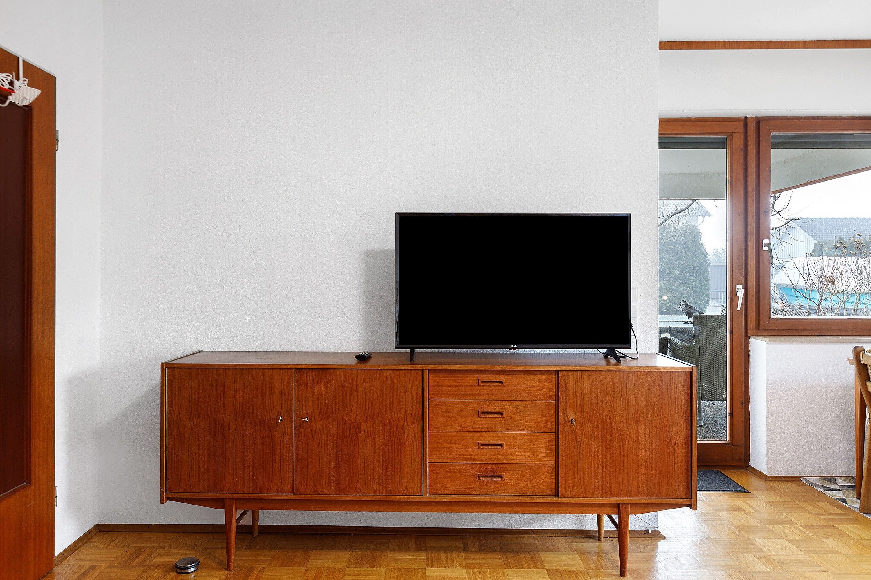 Ein Holzschrank mit einem Flachbildfernseher, einer Tür und einem Fenster mit Blick.