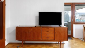 A wooden cabinet with a flat-screen TV, a door, and a window with a view. - Apartment Josef with Private Terrace (Radolfzell am Bodensee)