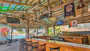 A beach bar with wooden furniture, a pool, and a thatched roof. - Family Friendly & Resort Perks! Perdido Key Condo (Pensacola)