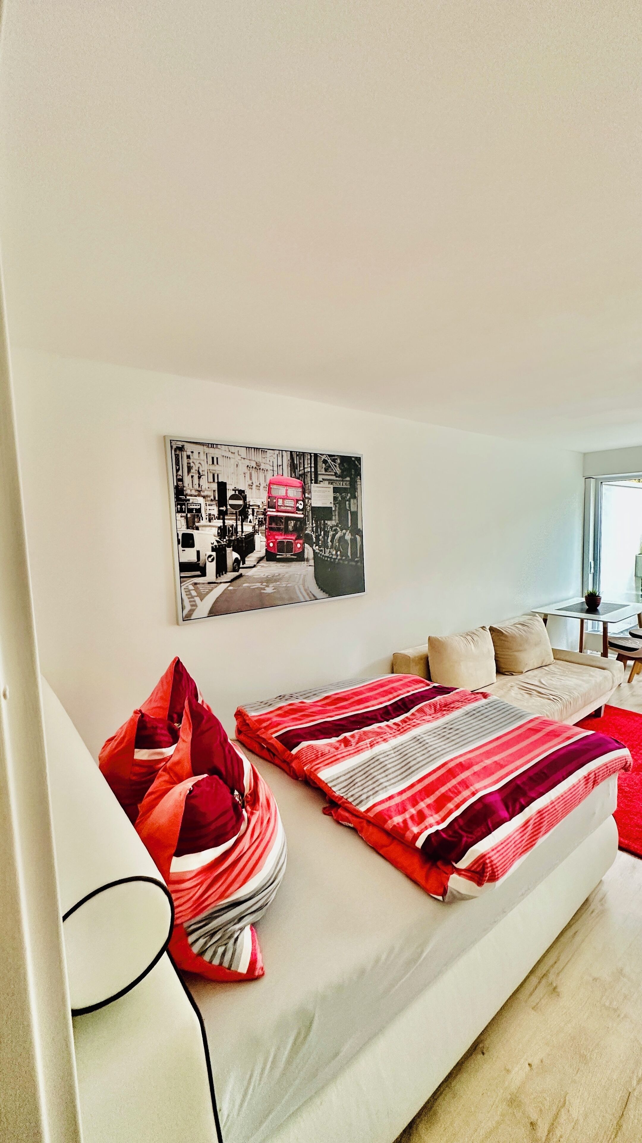 Ein modernes Schlafzimmer mit Bett, Kissen, einem Wandbild und einem Fenster.