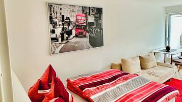 Ein modernes Schlafzimmer mit Bett, Kissen, einem Wandbild und einem Fenster.