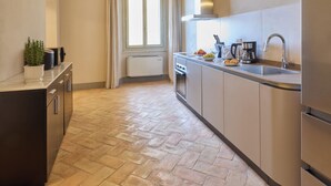 Una cocina moderna con horno empotrado, pileta de acero inoxidable y ventana con cortinas.