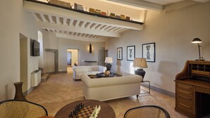 Un amplio salón con techo alto, chimenea, mesa de ajedrez y piano.