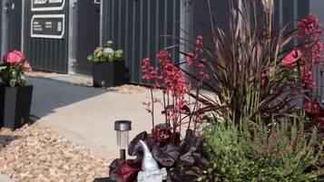 Portable restrooms with "SLEEP WELL" and "ROATEL" signs, surrounded by potted plants and a pathway.