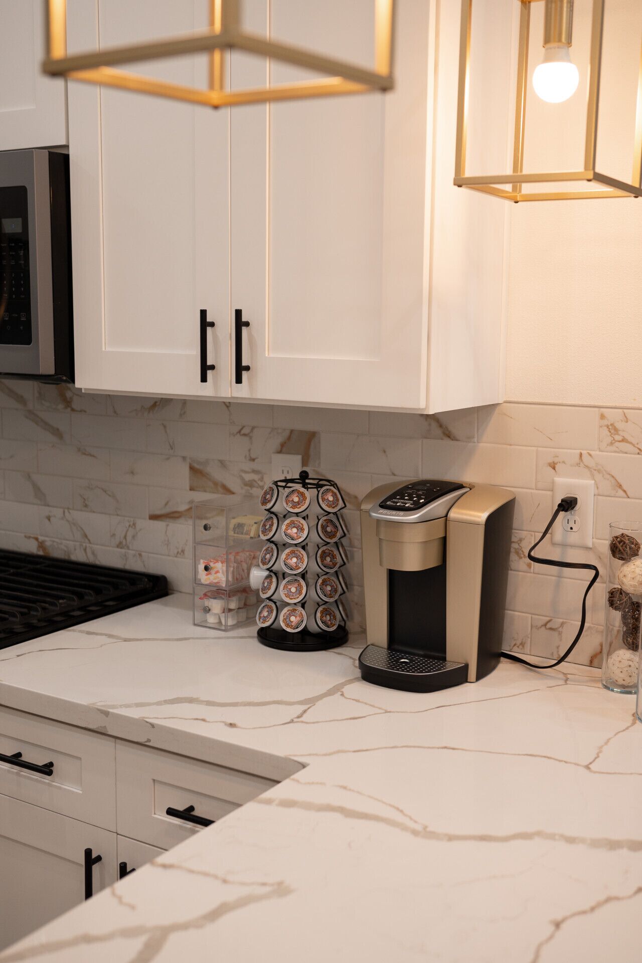 A kitchen with white cabinets, a coffee maker, and a glass container with decorative items.