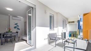 Un apartamento moderno con comedor, sofá, una mesa con objetos y un balcón con vistas.