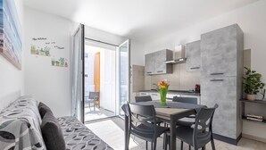 Una cocina moderna con armarios grises, una mesa de comedor con sillas y un sofá con cojines estampados.