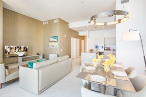 Ein modernes Wohnzimmer mit einer Couch, einem Esstisch für vier Personen und einer Küche im Hintergrund.