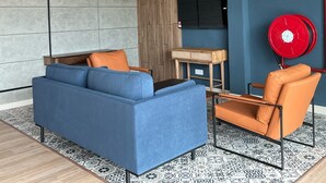 Ein modernes Wohnzimmer mit einem blauen Sofa, einem orangefarbenen Sessel und einem Holztisch.