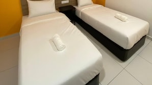 Ein Hotelzimmer mit zwei Einzelbetten, weißer Bettwäsche, einem Holzkopfende und einer orangefarbenen Wand.