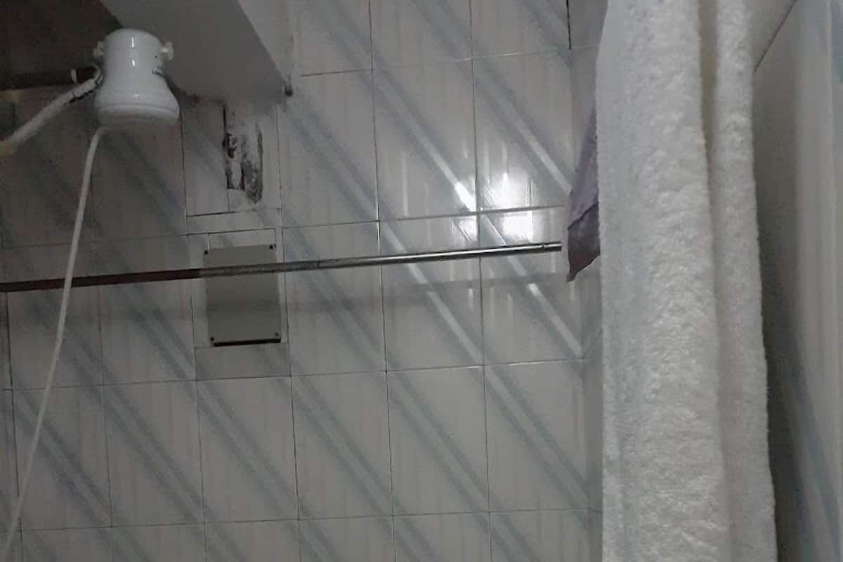 A bathroom with a tiled floor, a shower curtain, and a white towel hanging on a rack.