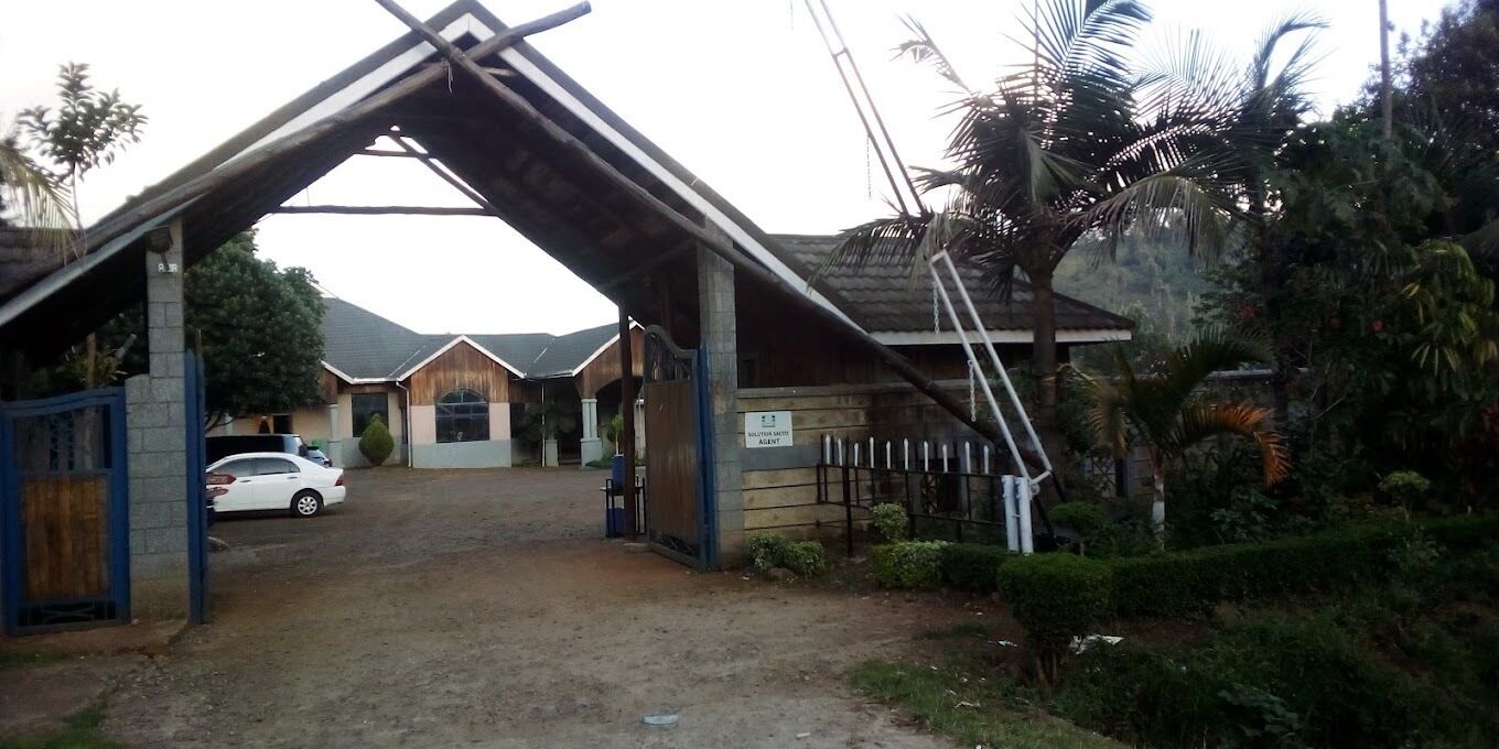 A gated entrance to a property with a car parked inside.