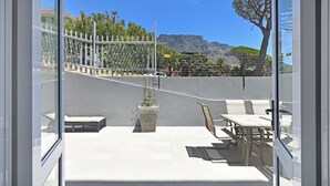 Une terrasse extérieure avec un espace salon, un bac à plantes en béton et une vue sur un paysage montagneux.
