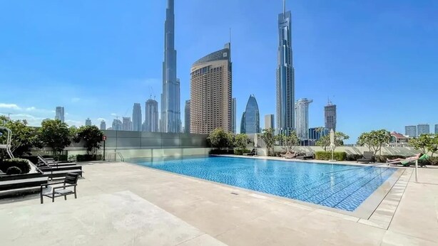 A swimming pool with a city skyline in the background. - StayShort - 2 Bed in Downtown Dubai that Sleeps 4 with Canal Views! (Downtown)