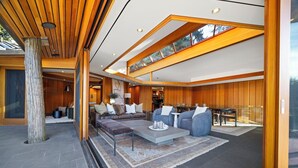 Un amplio salón con techo alto, vigas de madera y un ventanal grande.